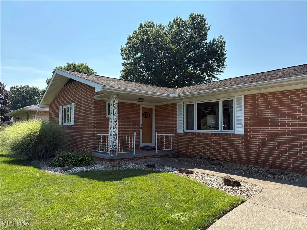 Single story home featuring a front lawn, brick siding, and a porch