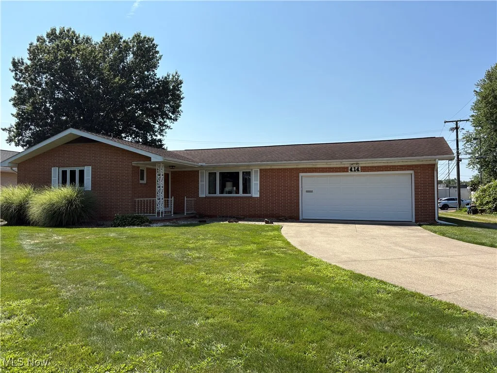 Ranch-style house featuring driveway, a garage, brick siding, and a front lawn