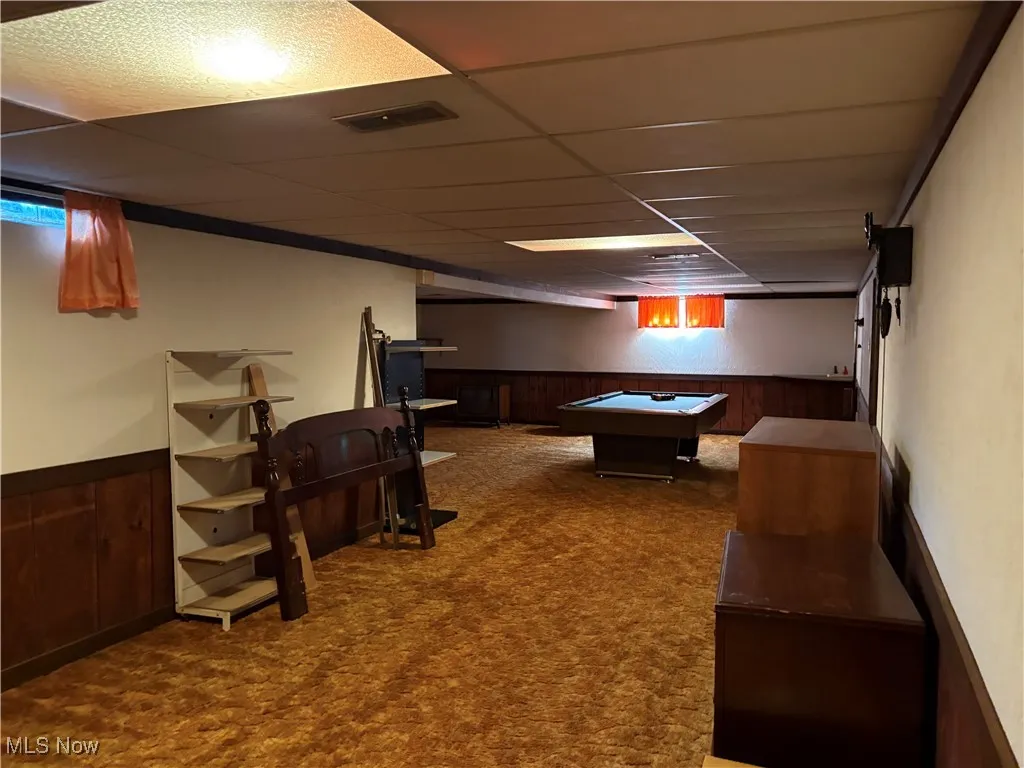 Recreation room with wainscoting, wooden walls, carpet, pool table, and a drop ceiling