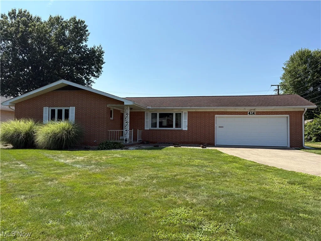 Ranch-style house featuring a garage, concrete driveway, brick siding, and a front yard