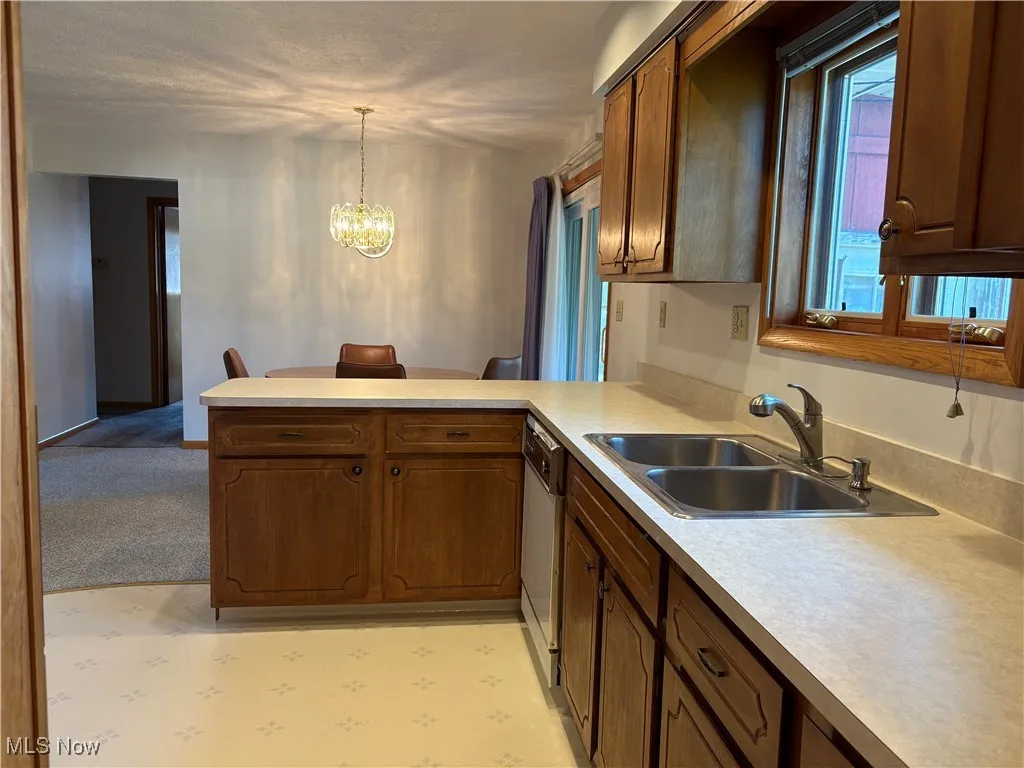 Kitchen featuring a chandelier, a peninsula, light countertops, and pendant lighting