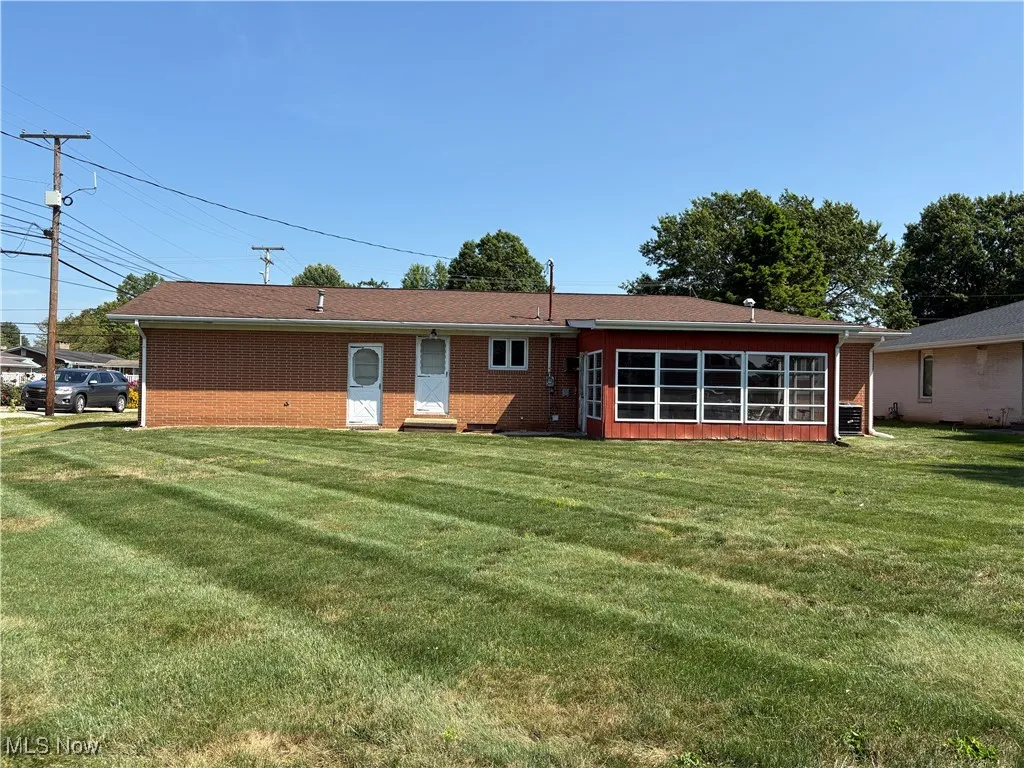 Rear view of house featuring a yard, a sunroom, and brick siding
