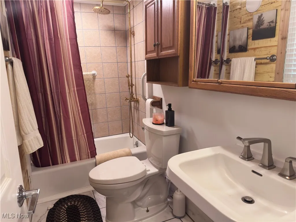 Bathroom featuring a sink and shower / bath combination with curtain
