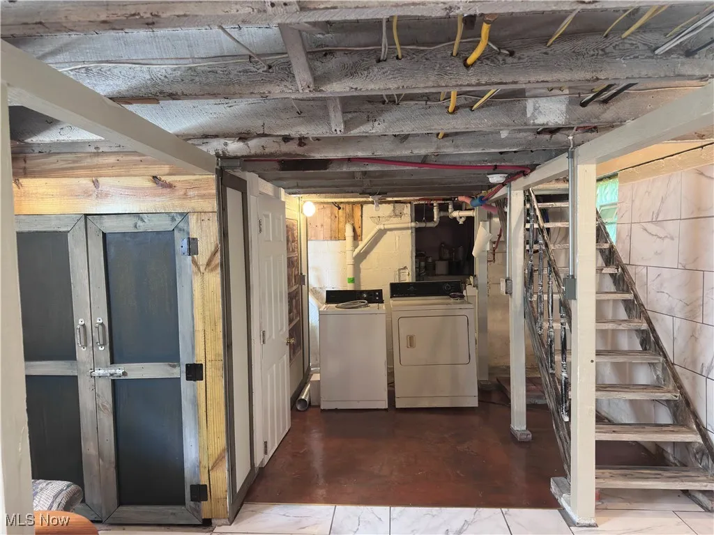 Unfinished basement with washing machine and clothes dryer and stairs