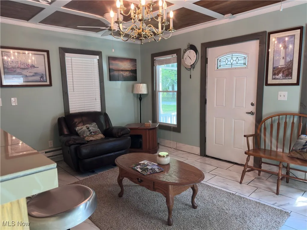 Living room featuring coffered ceiling, crown molding, and a chandelier