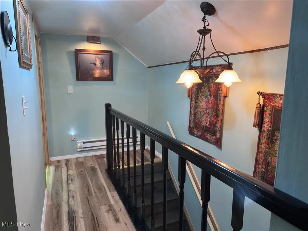 Stairs featuring lofted ceiling, wood finished floors, a baseboard radiator, and a baseboard heating unit