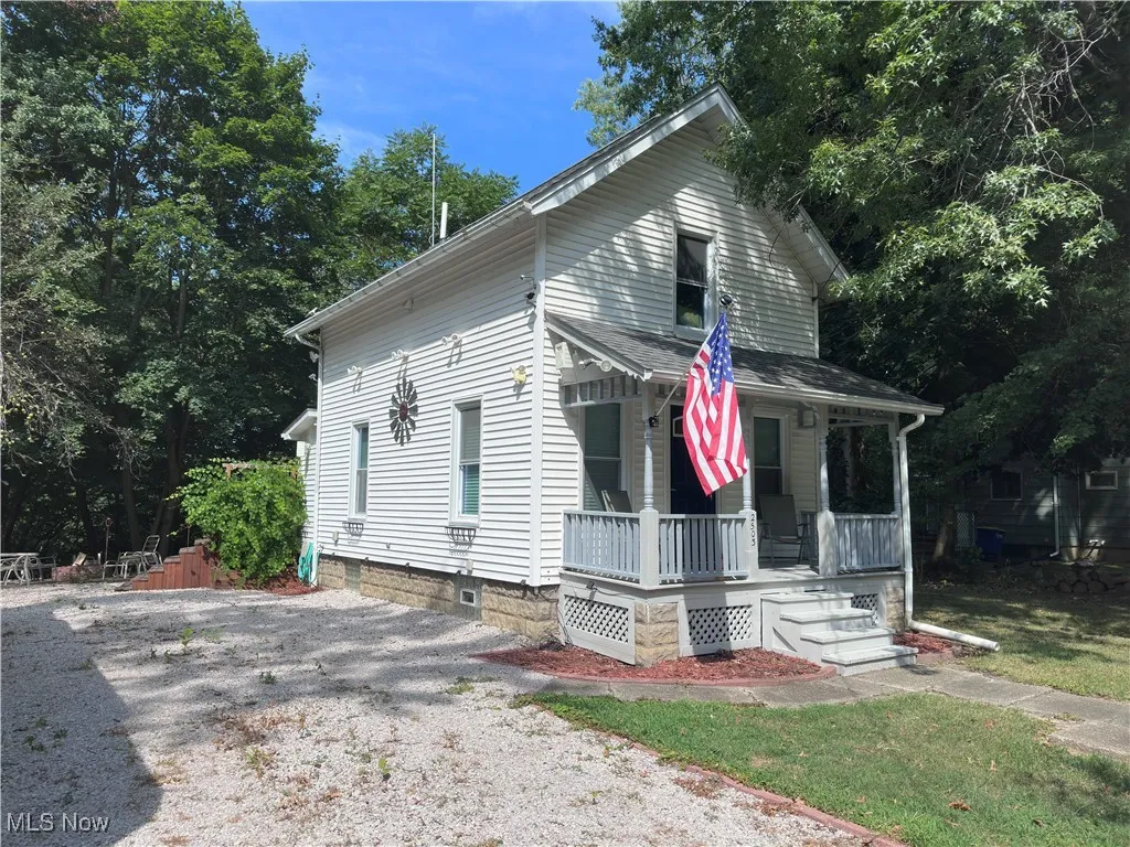 View of front of home featuring a porch and gravel driveway
