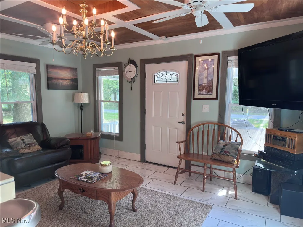 Living area featuring wood ceiling, ornamental molding, and a chandelier