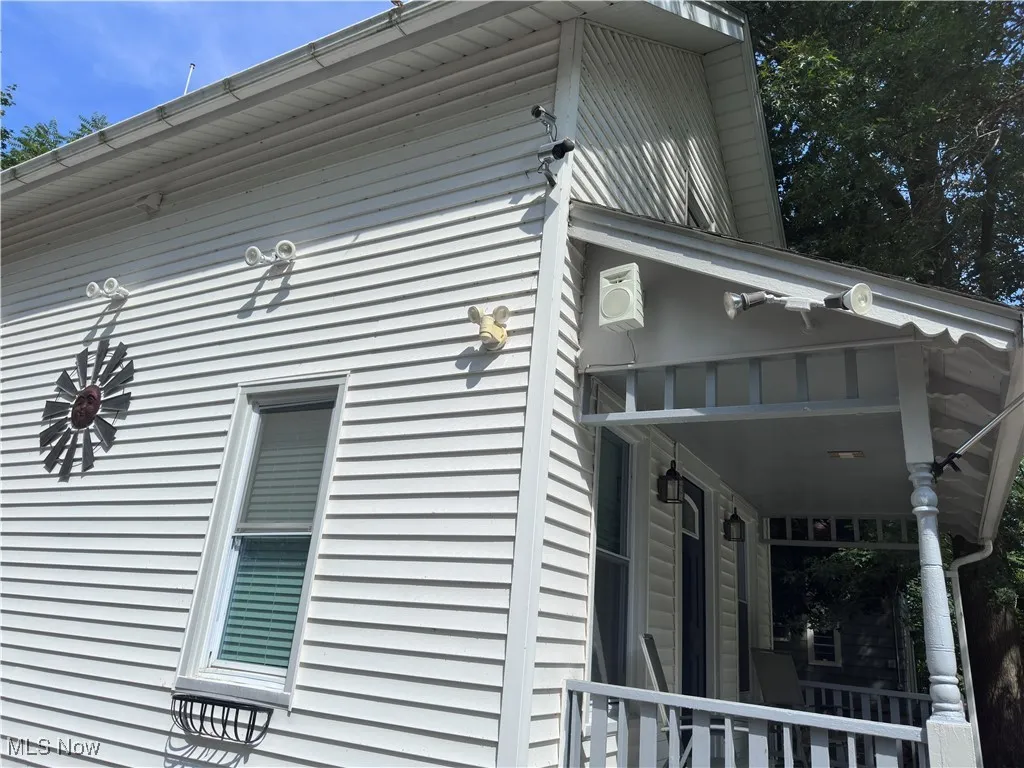 View of home's exterior with covered porch and outdoor speakers.
