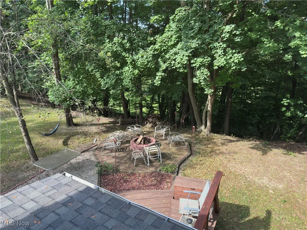 View of grassy yard featuring a wooden deck and a patio