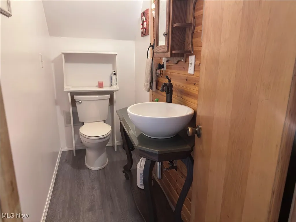 Half bath with wood finished floors and toilet
