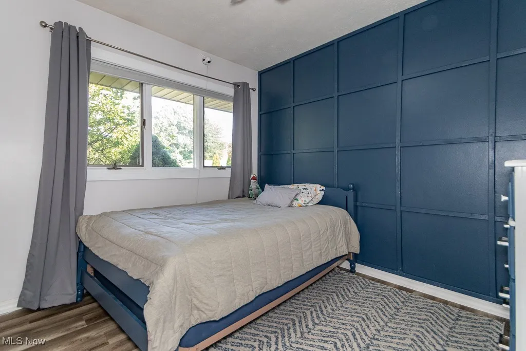 Bedroom with wood finished floors and a decorative wall