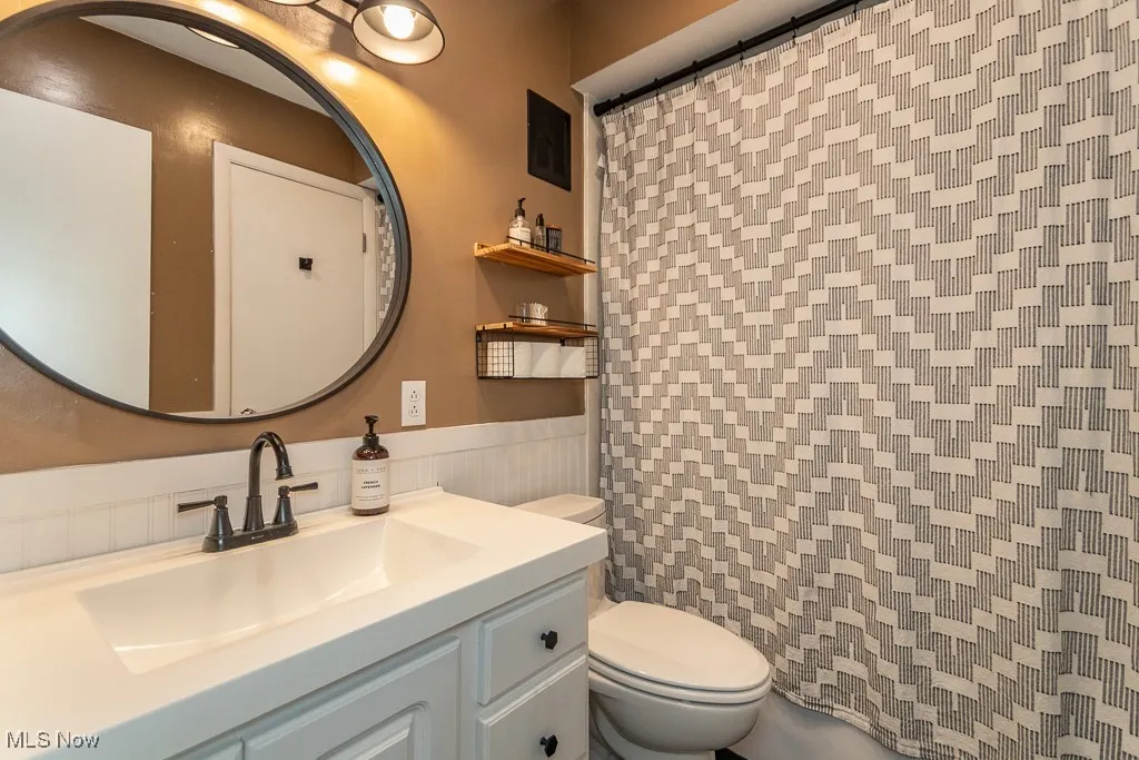 Full bathroom with vanity and wainscoting