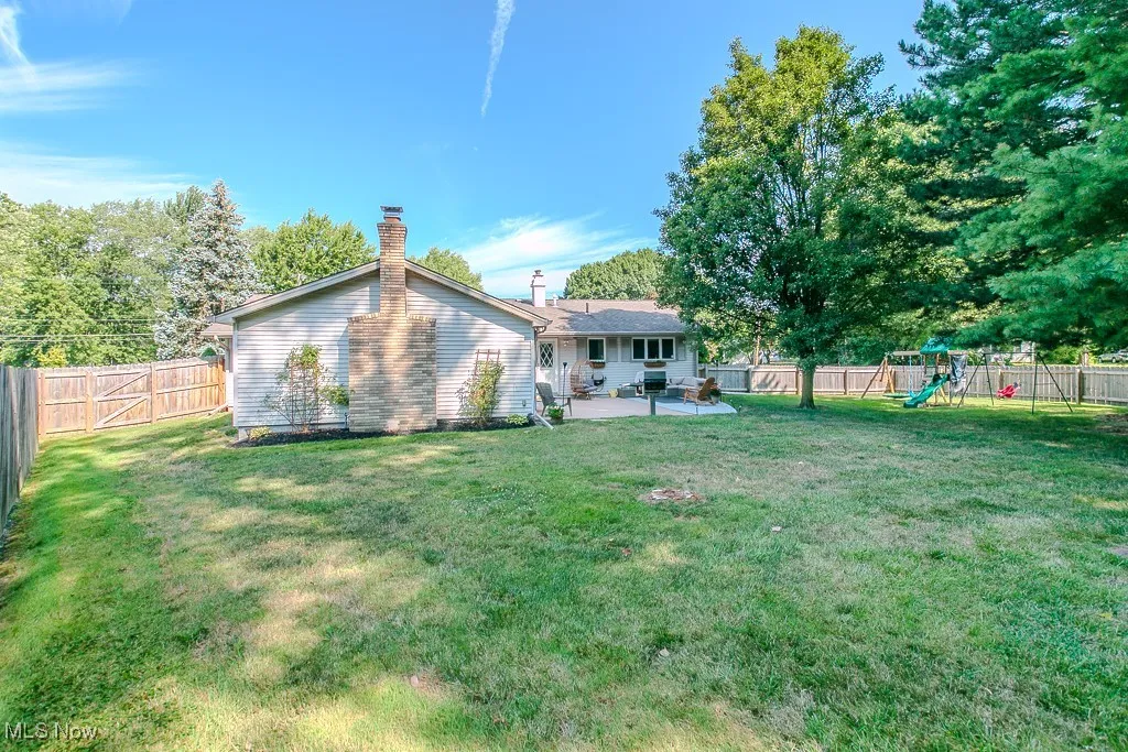 Back of property with a patio, a fenced backyard, a playground, and a chimney