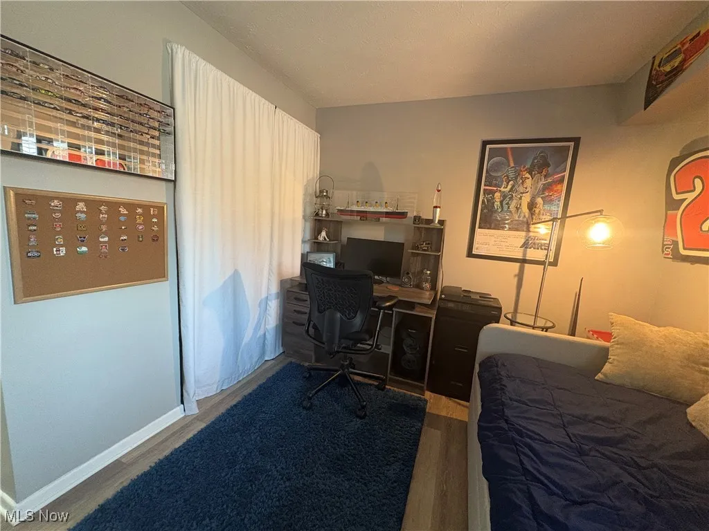 Bedroom featuring wood finished floors and an office area