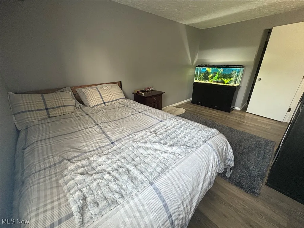 Bedroom with wood finished floors and a textured ceiling