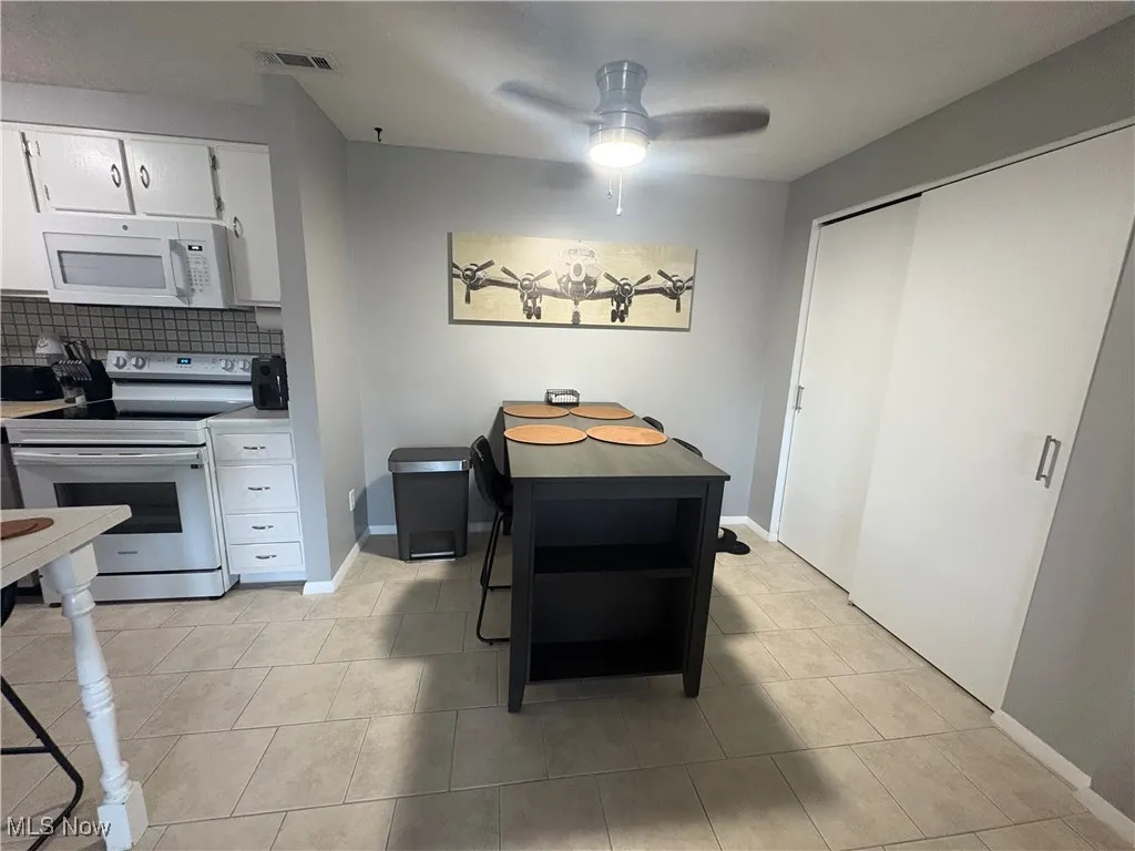 Kitchen featuring white appliances, tasteful backsplash, white cabinetry, and light tile patterned floors