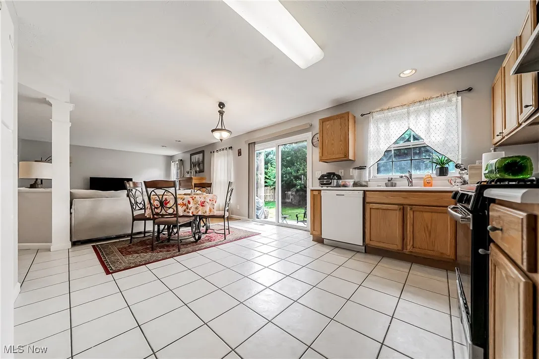Kitchen with black electric range, light tile patterned floors, light countertops, dishwasher, and open floor plan