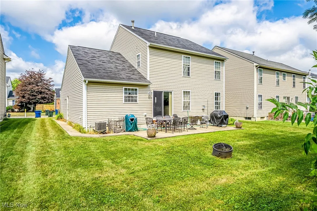 Back of property with a patio area, a fire pit, a yard, and a shingled roof