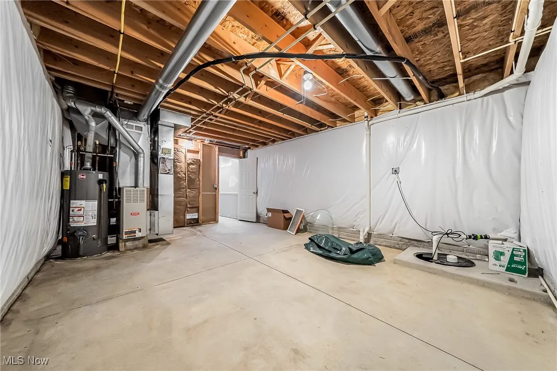 Unfinished below grade area featuring gas water heater and heating unit