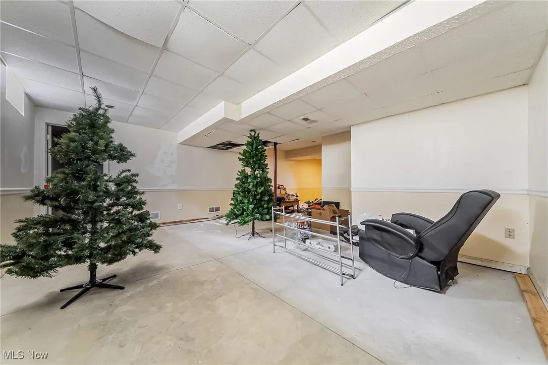 Sitting room featuring a drop ceiling and concrete floors