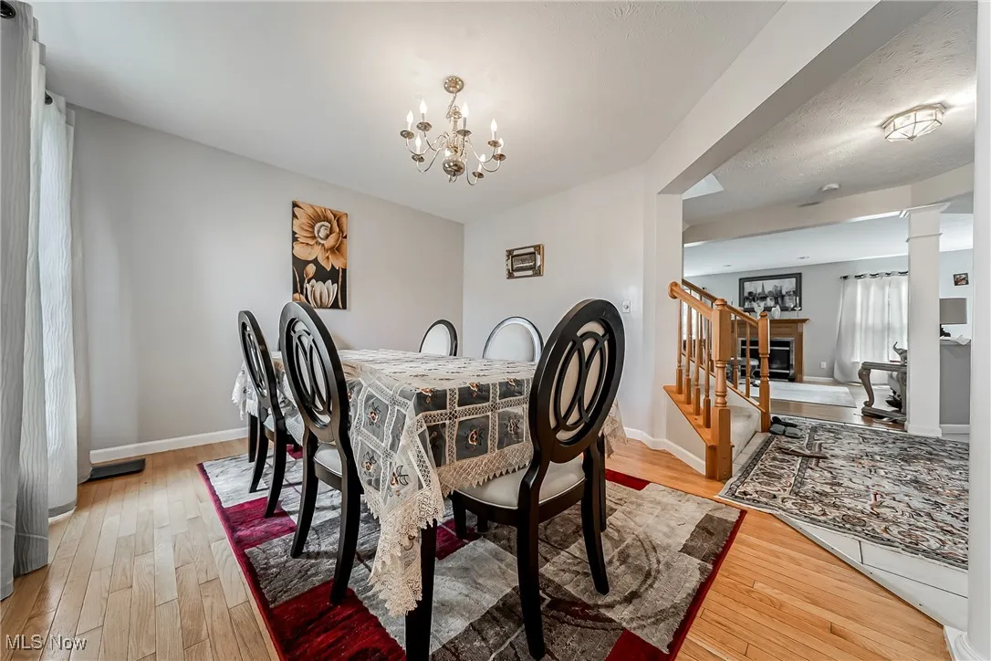 Dining area with light wood-style floors, a chandelier, stairway, and a textured ceiling