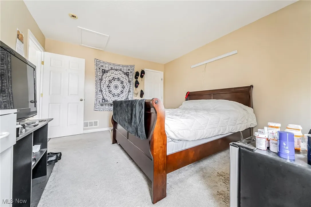 Carpeted bedroom featuring attic access and baseboards