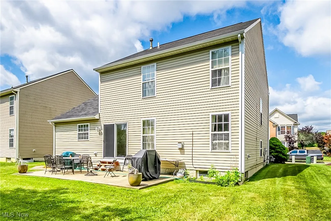 Rear view of property with a lawn and a patio