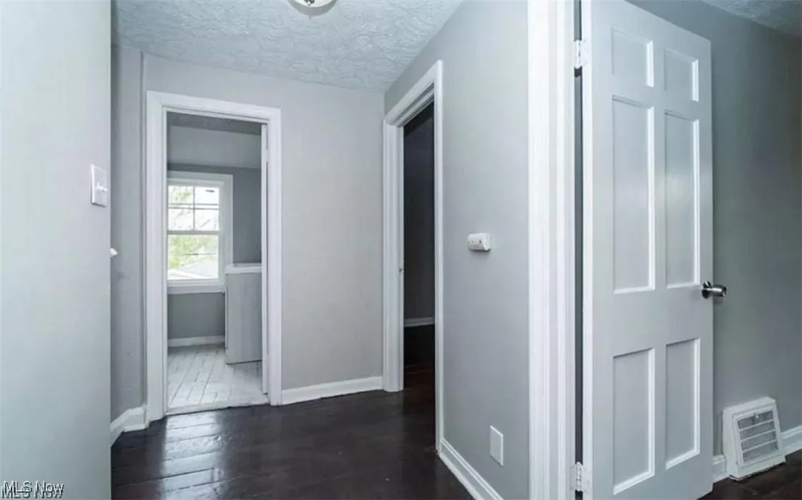Corridor featuring a textured ceiling and dark wood-style flooring