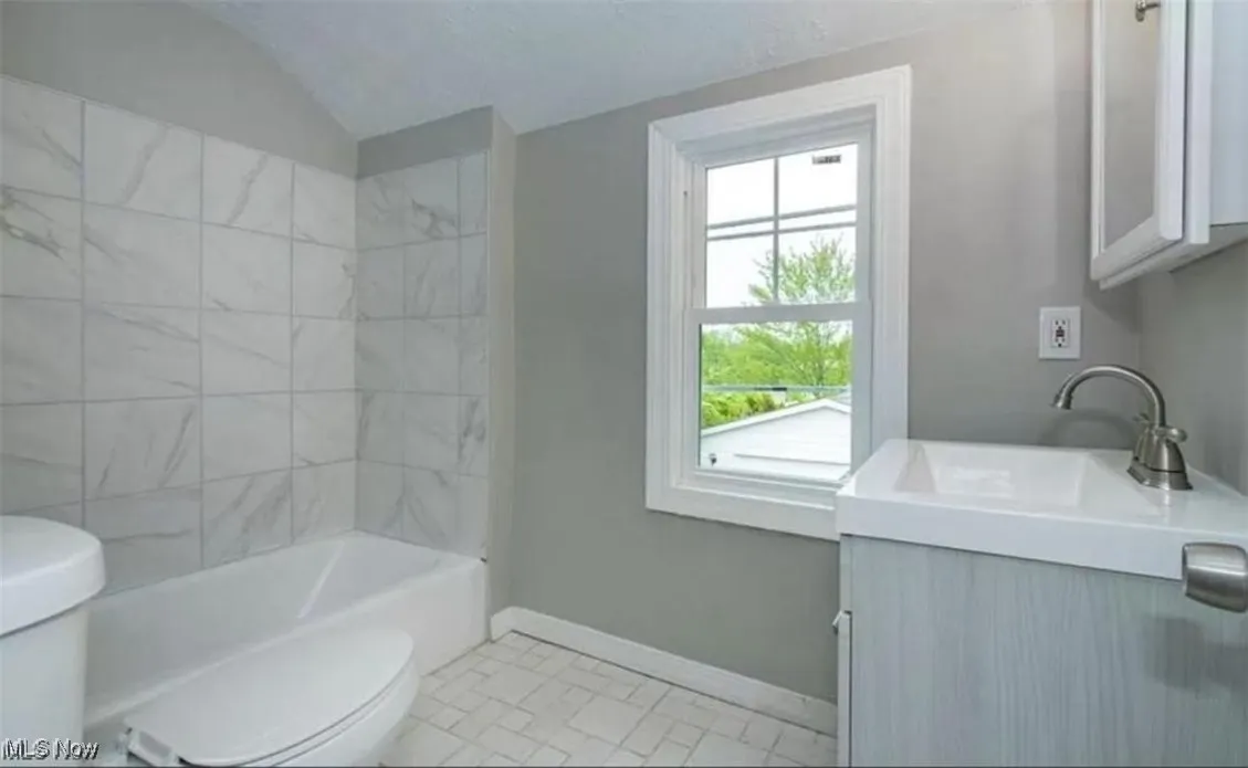 Full bathroom with vanity, lofted ceiling, tile patterned floors, and bathing tub / shower combination