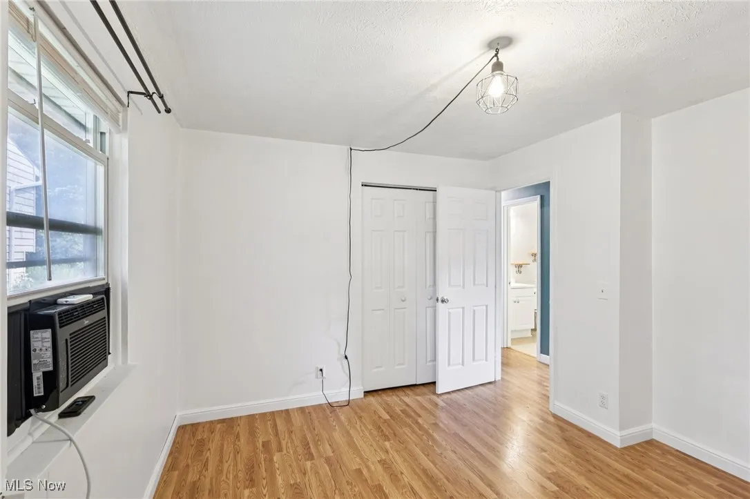 Unfurnished dining area featuring light wood-style flooring, cooling unit, and a textured ceiling