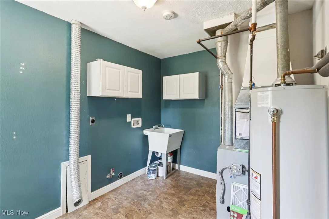 Washroom with electric dryer hookup, cabinet space, gas water heater, hookup for a washing machine, and gas dryer hookup