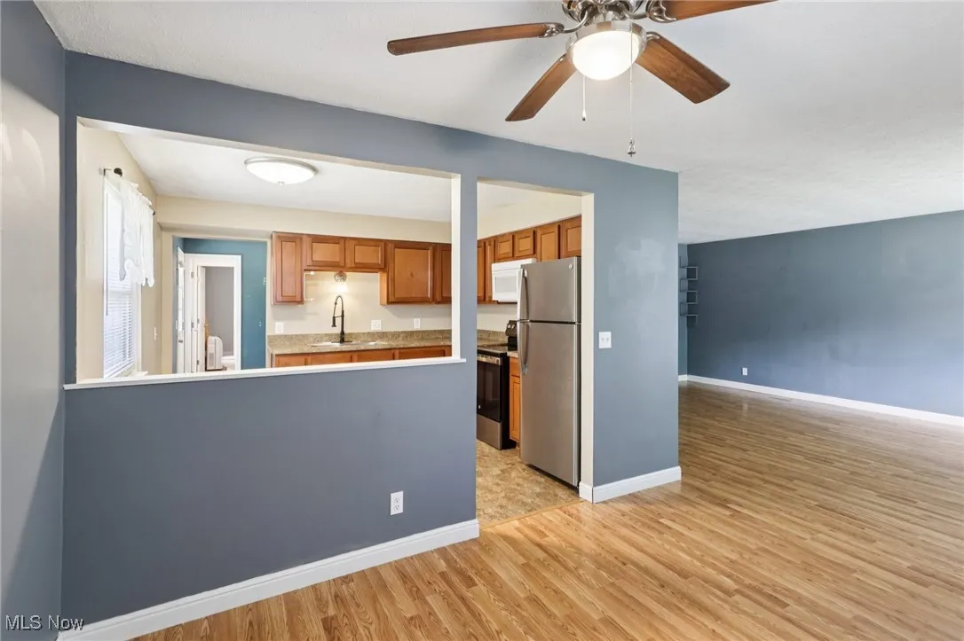 Kitchen featuring stainless steel appliances, light wood finished floors, brown cabinets, ceiling fan, and a peninsula