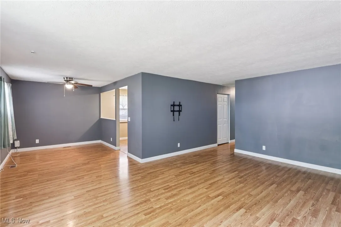 Empty room featuring light wood-style flooring, a ceiling fan, and a textured ceiling