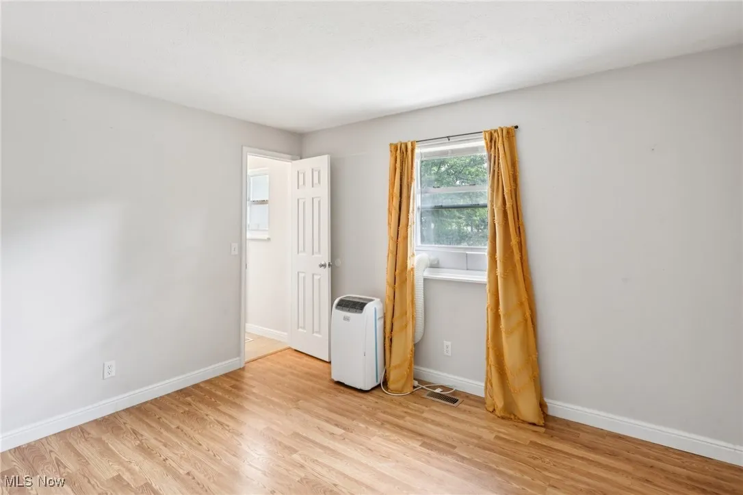 Empty room with baseboards and light wood-type flooring