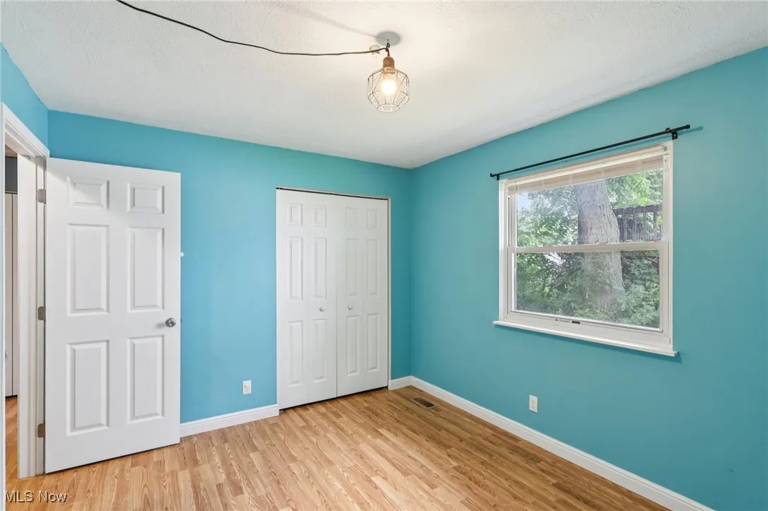 Unfurnished bedroom with light wood-style floors, a closet, and a textured ceiling