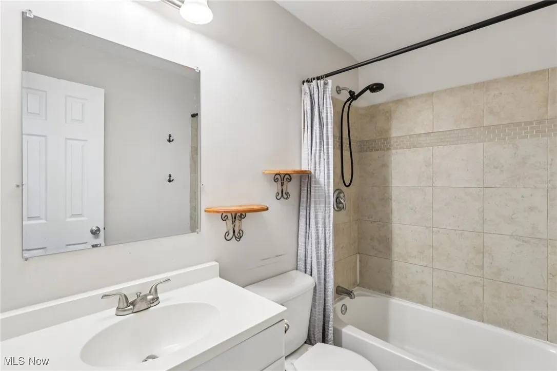 Bathroom featuring shower / bath combination with curtain and vanity