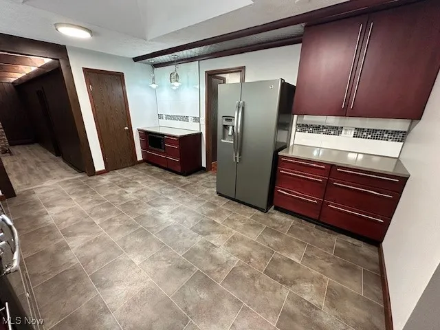 Kitchen featuring stainless steel fridge, decorative backsplash, reddish brown cabinets, light countertops, and built in microwave