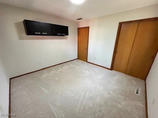 Unfurnished bedroom featuring light colored carpet and a closet