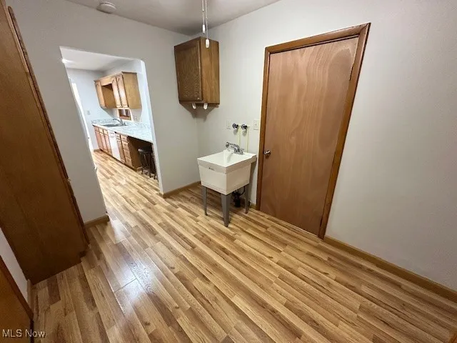 Laundry room featuring light wood-type flooring and baseboards