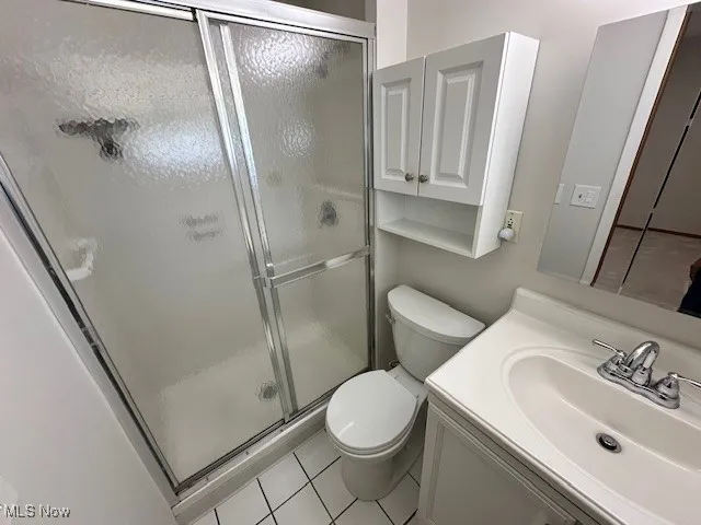 Full bathroom featuring tile patterned flooring, a stall shower, and vanity
