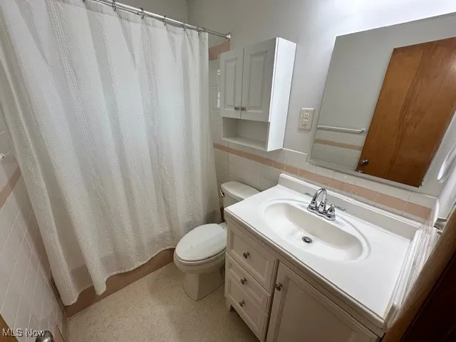 Full bathroom featuring tile walls, vanity, a shower with curtain, and decorative backsplash
