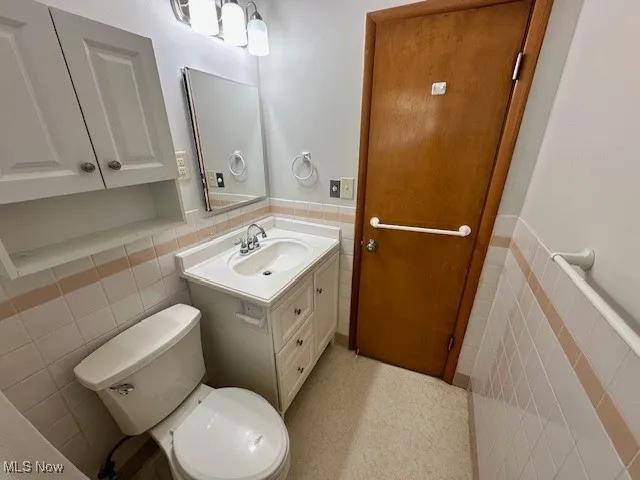 Bathroom with tile walls, a wainscoted wall, and vanity