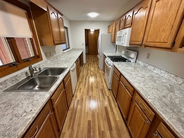 Kitchen featuring light wood-type flooring, white appliances, and light countertops