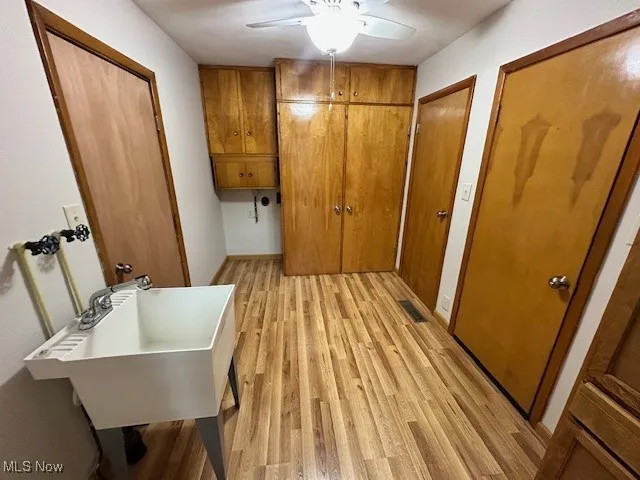 Laundry area with cabinet space, light wood finished floors, and ceiling fan