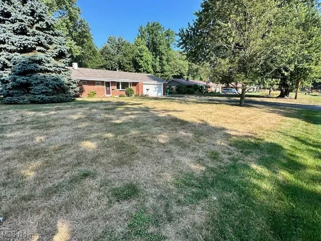 View of front facade with a front lawn, a chimney, and an attached​​‌​​​​‌​​‌‌​‌‌​​​‌‌​‌​‌​‌​​​‌​​ garage