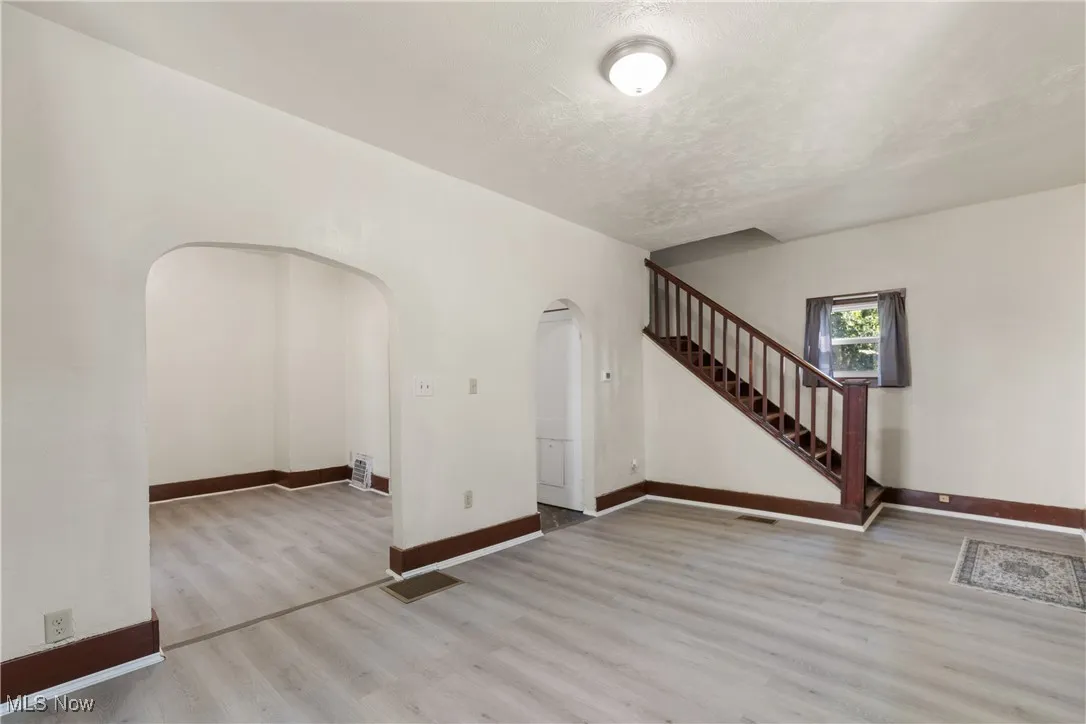 Unfurnished living room with wood finished floors, a textured ceiling, and stairs