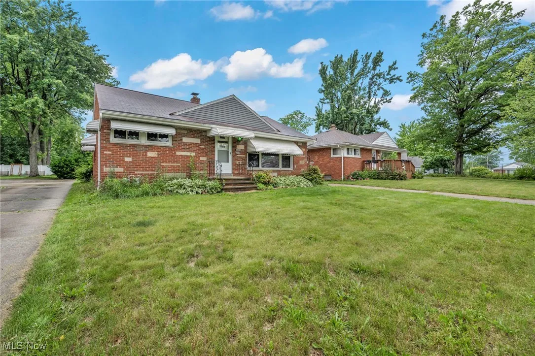 View of front of home featuring brick siding, a chimney, a front lawn, and driveway