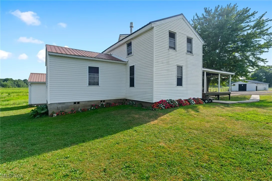 View of property exterior featuring a metal roof and a yard