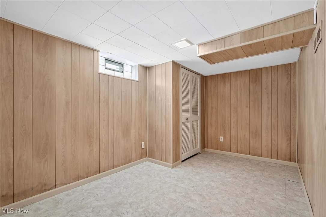 Basement with wood walls and tile patterned floors